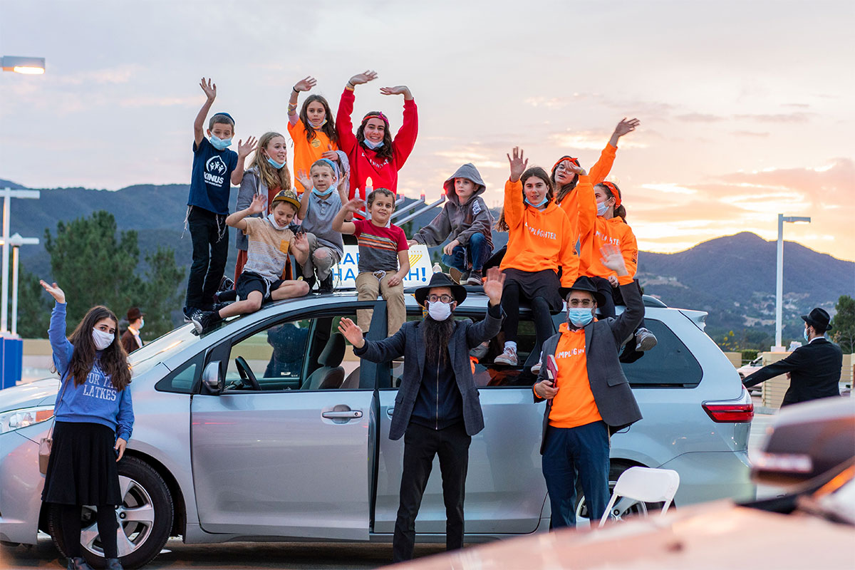 Group of people standing on car waiving arms