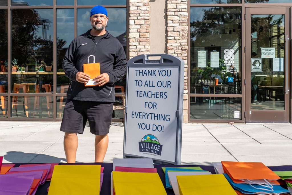 Man holding bag in front of Wave of Kindness sign