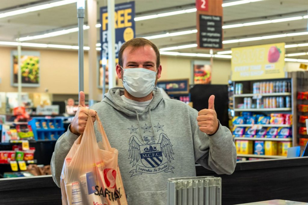 Man in supermarket holding bag of groceries