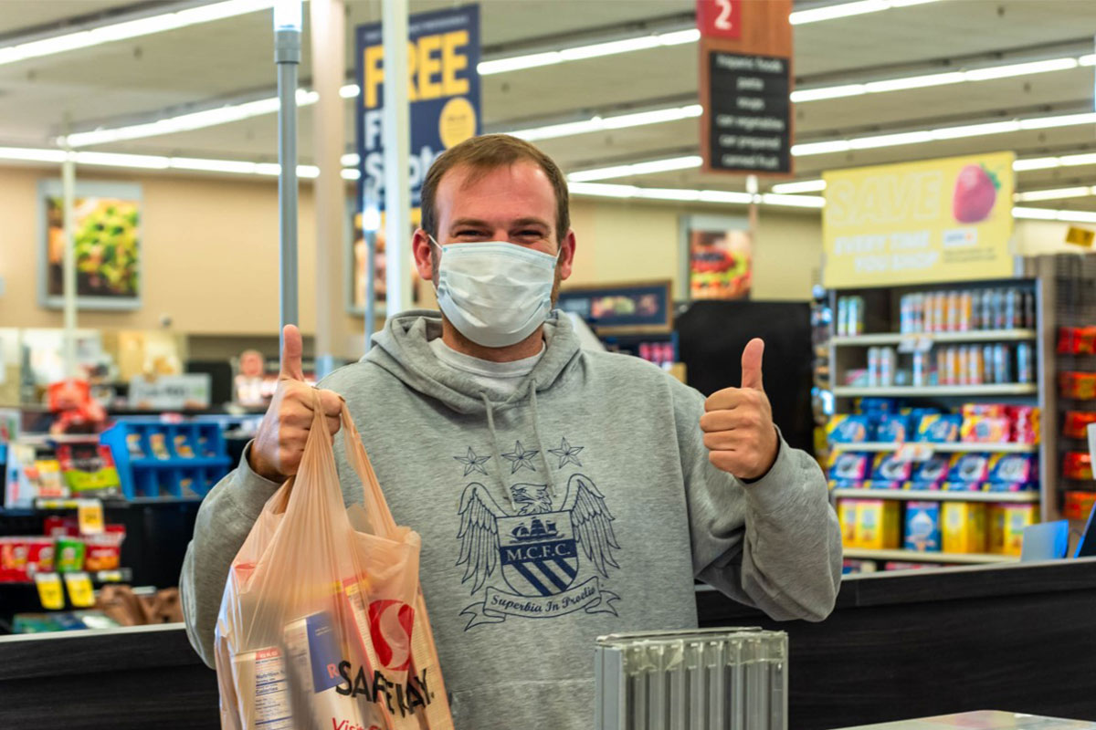 Man in supermarket holding bag of groceries